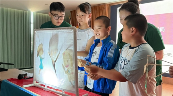 实践团成员教授天山乡榆树沟村的孩子们进行皮影操作。尹晓伟供图